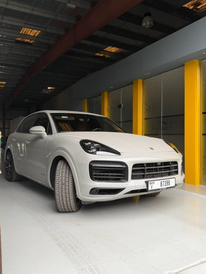 A white Porsche Cayenne GTS at the BavarLand workshop entrance